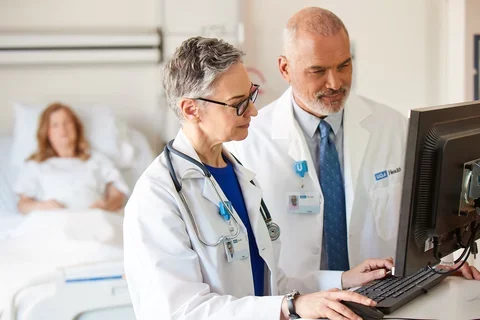 Two physicians on computer and patient in background