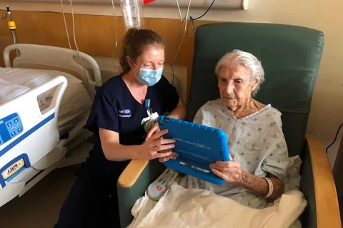 Image of UCLA Health nurse helping a patient use the bedside devices.