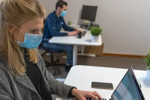 Image of masked staff on laptops