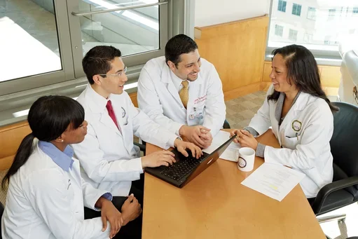 Four clinicians sitting around laptop
