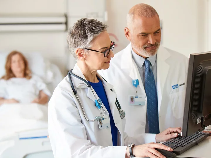 Two physicians on computer and patient in background