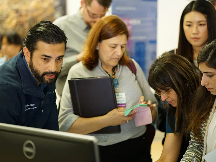A group of individuals focused on a computer screen, eagerly observing its display.