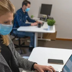 Image of masked staff on laptops