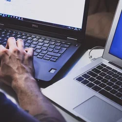 Person working on two laptops