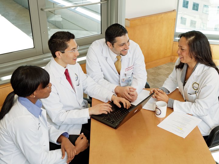 Four clinicians sitting around laptop
