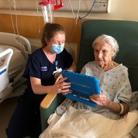 Image of UCLA Health nurse helping a patient use the bedside devices.
